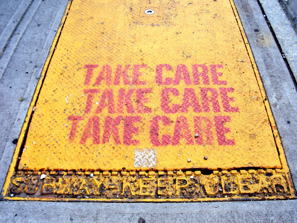 image of a metal door that is painted yellow and in red says, "Take care" three times