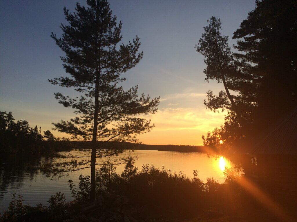 sunset on a lake, surrounded by trees